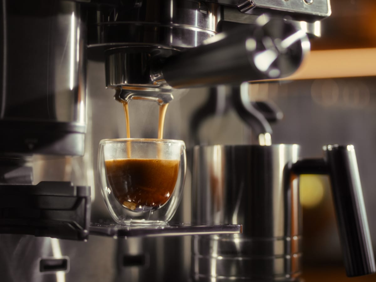 Fresh espresso pouring from portafilter into double-walled glass